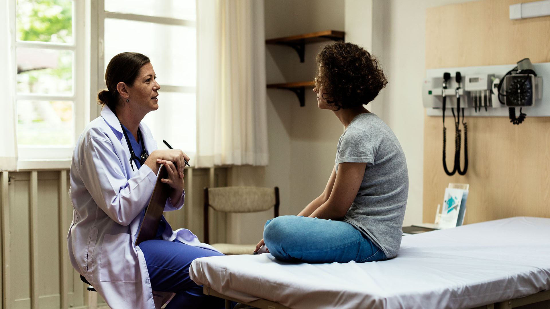 Doctor Speaking With Patient In A Hospital Regarding Injury Or Illness.