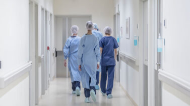 Medical professionals walking through a hospital hallway.