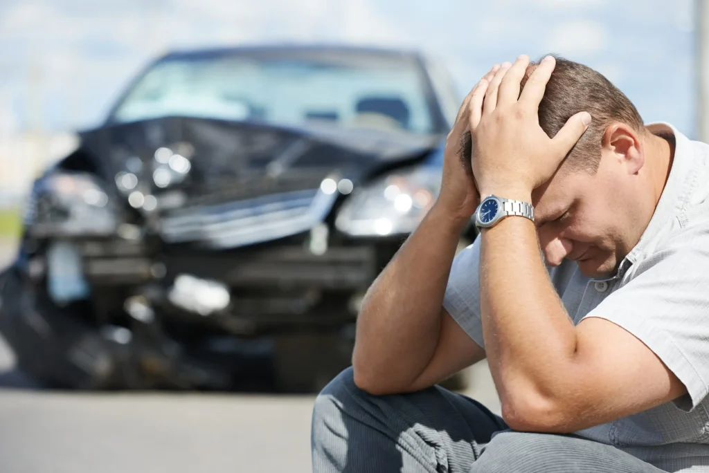Man Sitting on Road After Car Accident