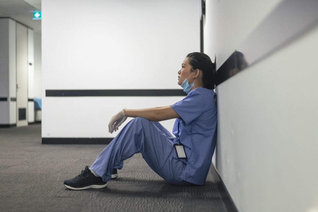 A female nurse sits on the hospital hallway floor. 