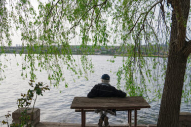 Man awarded workers compensation payout for workplace eye injury sitting on bench in front of lake